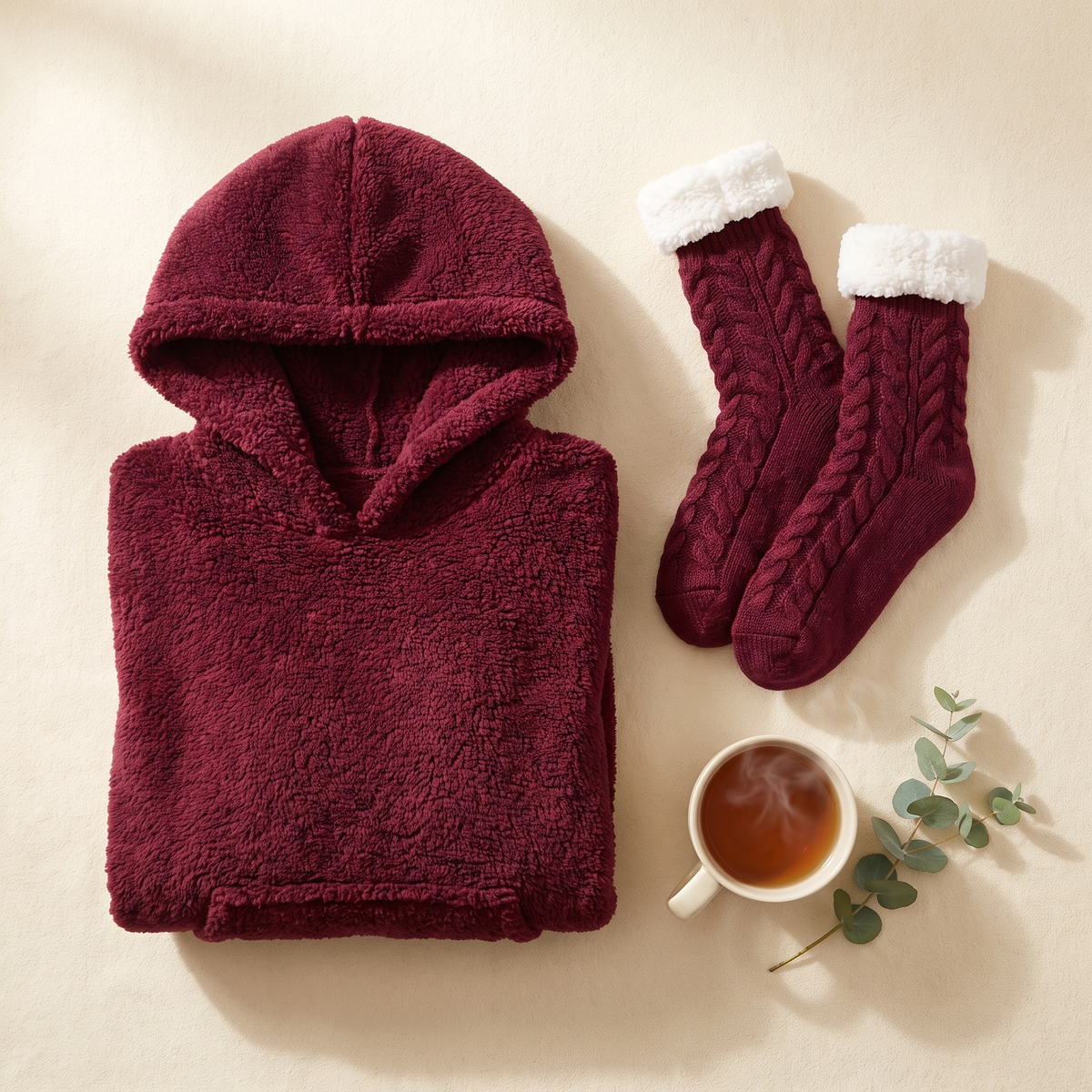 Wine red Hibernation Hoodie folded beside matching wine red cable knit slipper socks