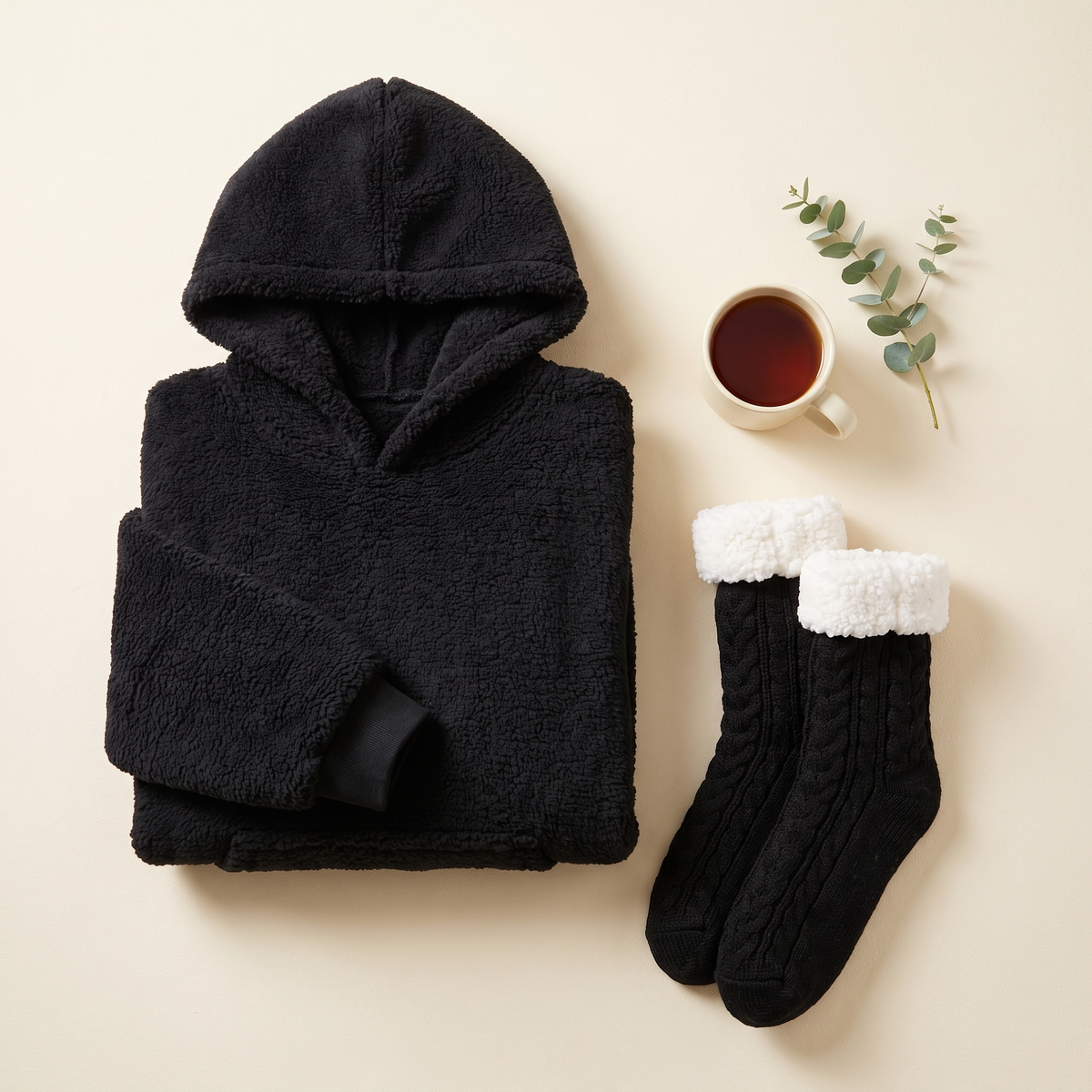 Black Hibernation Hoodie folded beside matching black cable knit slipper socks